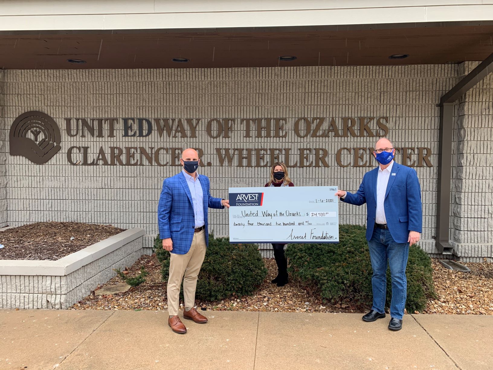 image of Kyle Hubbard, President of Arvest Bank-Springfield, and Pam Yancey, a UWO Board member and Community Market Director, EVP of Arvest Bank, and Greg Burris, President and CEO of United Way of the Ozarks, holding a check in front of the United Way building