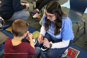 Photo of volunteer fitting child with new shoes
