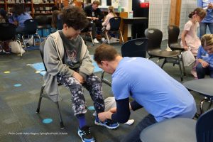 Photo of volunteer fitting child with new shoes
