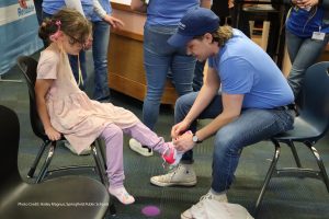 Photo of volunteer fitting child with new shoes