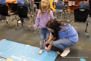 Photo of volunteer sizing a child's foot for new shoes