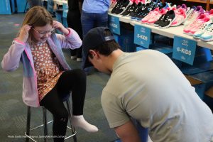 Photo of volunteer fitting child with new shoes