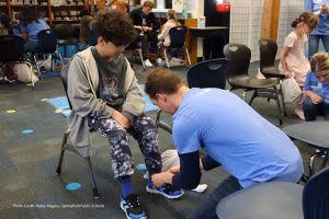 Photo of volunteer fitting child with new shoes