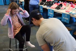 Photo of volunteer fitting child with new shoes